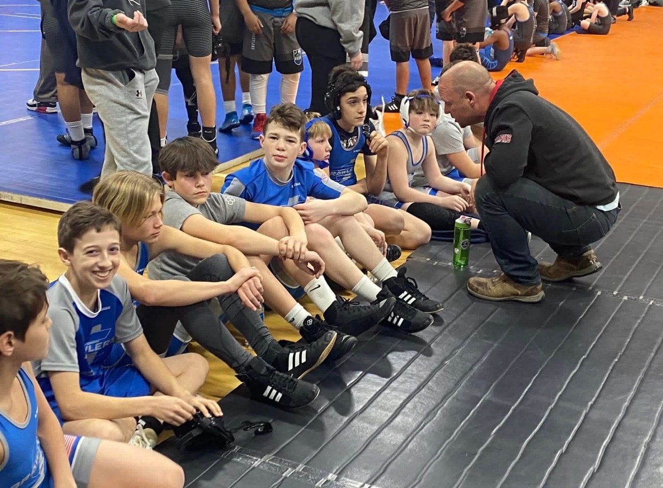 JC Brawlers athletes and coaches in a team huddle at a tournament